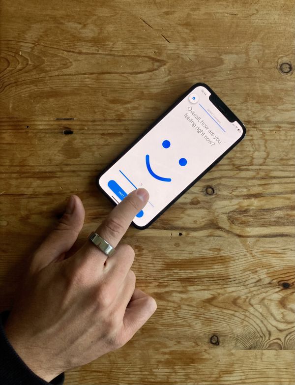 Pointed finger wearing a smart ring hovering over an iPhone